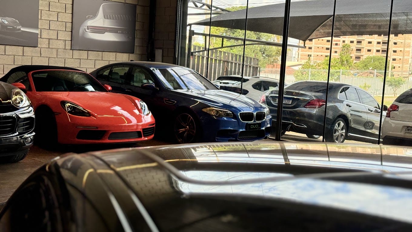 Showroom da DUO MOTORS com Porsche, BMW e Mercedes estacionados lado a lado